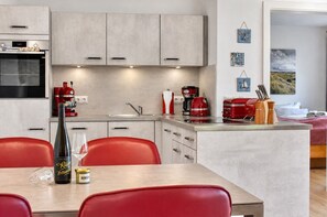 Une cuisine moderne avec un îlot central, des chaises rouges et une table à manger.