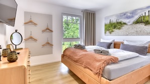 Un dormitorio con cama, cómoda de madera y un ventanal grande.