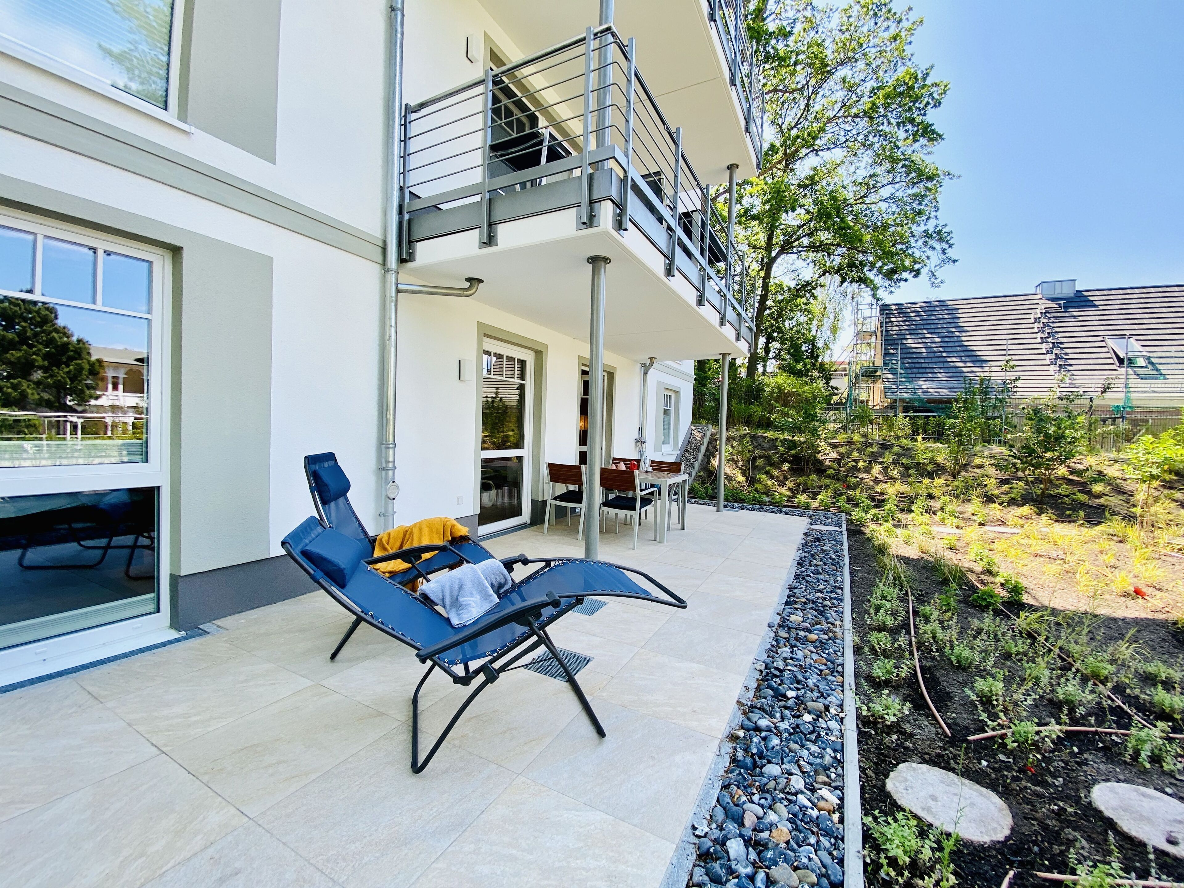 Un bâtiment moderne doté d’un balcon, d’un espace extérieur aménagé pour s’asseoir et d’un jardin.
