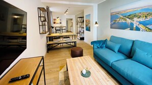 Uma sala de estar moderna com uma televisão grande, um espaço de refeições e um sofá com vista para a cidade.