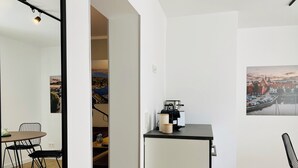 Una cocina moderna con cafetera, refrigerador pequeño y comedor con mesa y sillas.