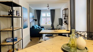 Una sala moderna con una mesa de comedor de madera, un sofá azul y una estantería.