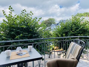 Ein Balkon mit Tisch für zwei Personen, einem Stuhl und Blick auf Häuser im Hintergrund.