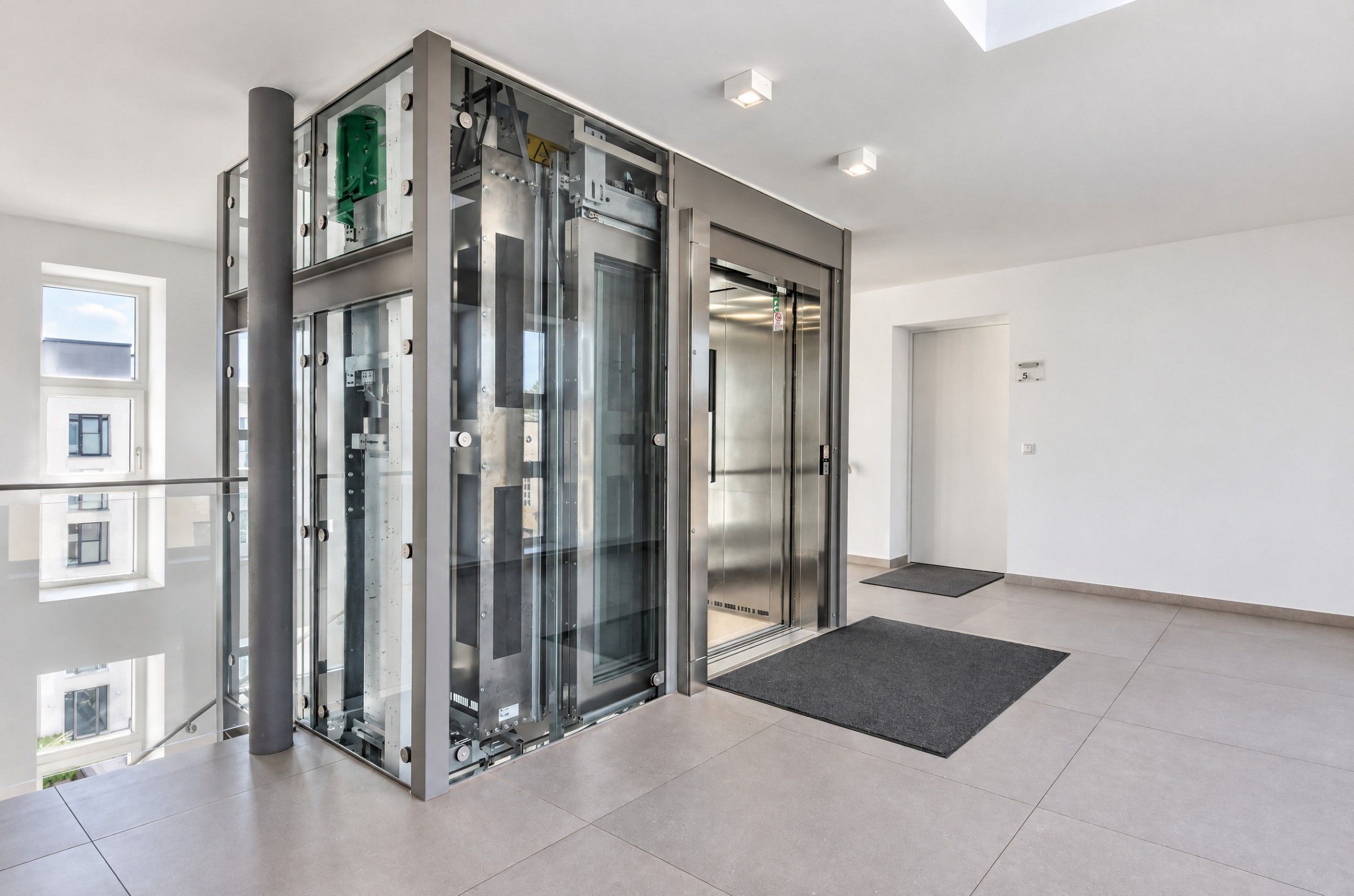 Ein moderner Aufzug mit Glasverkleidung, Metallstruktur und übersichtlichem Grundriss.