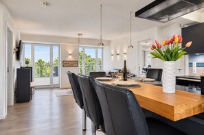 A modern kitchen with a wooden island, black chairs, and a vase of tulips.