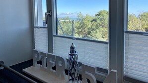 A room with large windows offering a view of trees and a distant structure.