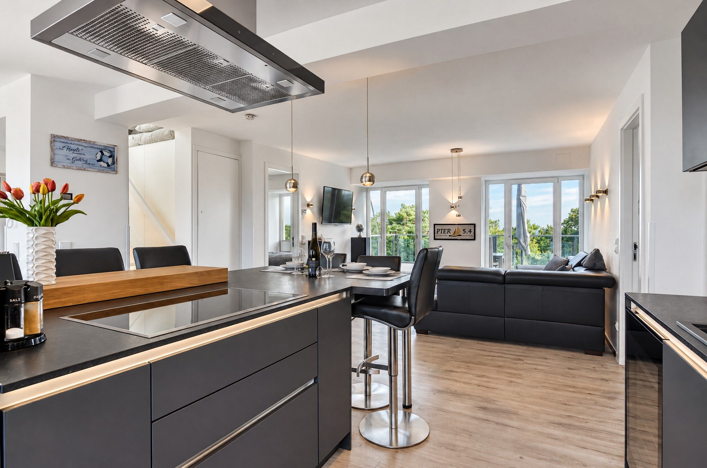 Een moderne keuken met een centraal eiland, barkrukken en een eethoek.