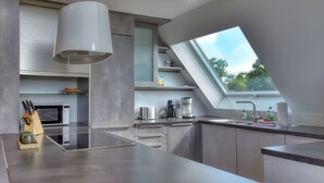Una cocina moderna con tragaluz, electrodomésticos de acero inoxidable y horno empotrado.