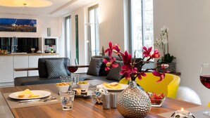 A modern dining area with a wooden table set for a meal, a vase with flowers, and a cityscape painting on the wall. - "My time out": Luxurious wellness suite with pool, sauna & infrared cabin (Binz)