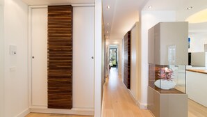 A modern hallway with wooden slats, a glass display case, and a kitchen area. - "My time out": Luxurious wellness suite with pool, sauna & infrared cabin (Binz)