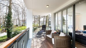 A balcony with wicker furniture, a bed, and a view of trees and buildings. - "My time out": Luxurious wellness suite with pool, sauna & infrared cabin (Binz)
