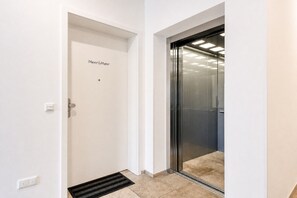 A clean, modern elevator with a glass door and a control panel on the wall.