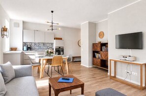 A modern apartment with a kitchen, dining area, living room, and a TV.