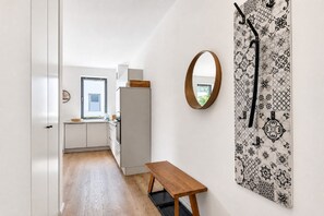 Un corridoio con una panca di legno, una porta bianca e un muro decorato.