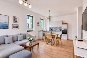 A modern living room with a grey sofa, a wooden coffee table, and a dining area with a table and chairs.