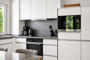 Eine moderne Küche mit weißen Schränken, einem eingebauten Backofen und einer Kaffeemaschine.