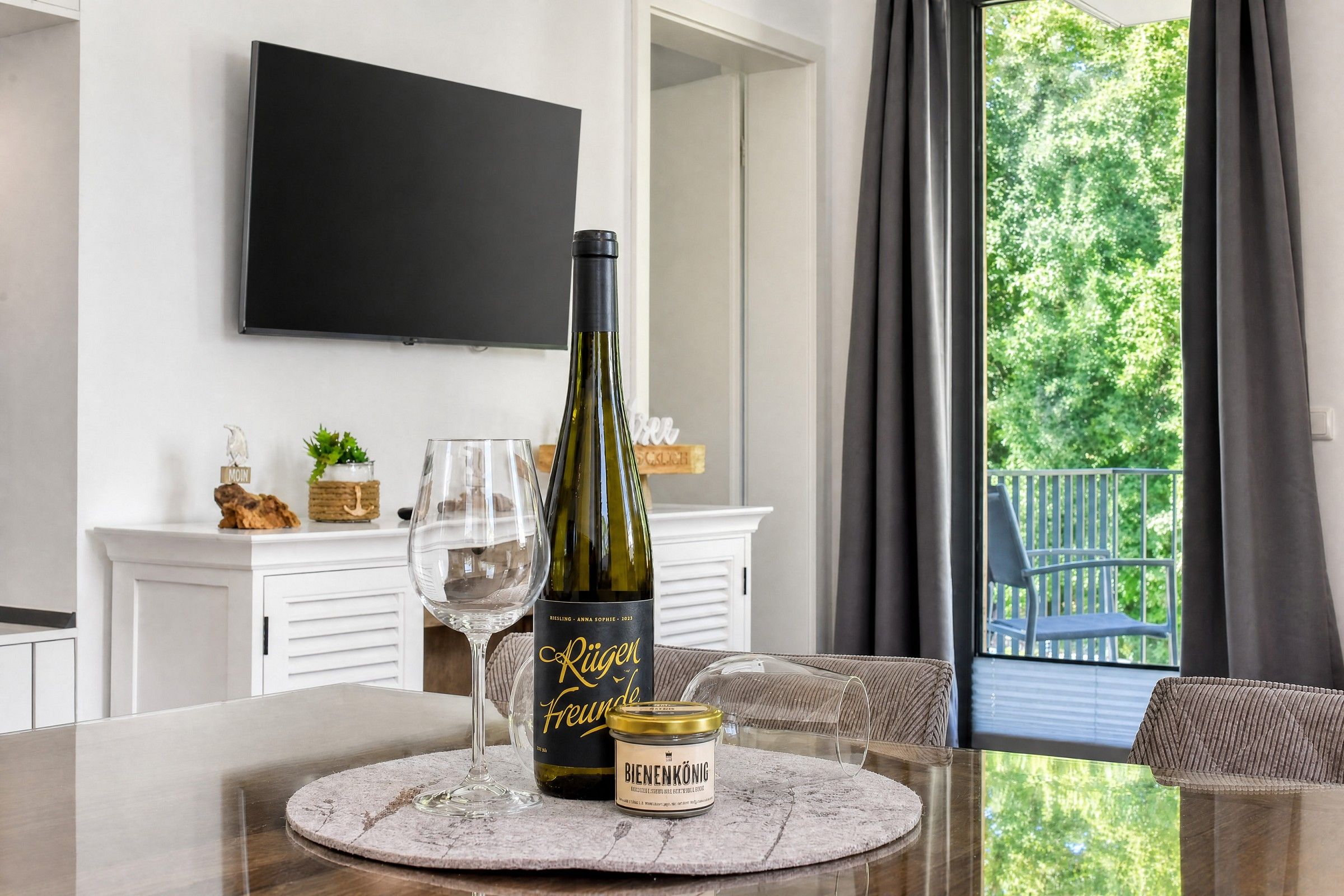 Ett matbord med en flaska Rieslingvin, ett vinglas och en burk Bienenkönig på en servett.