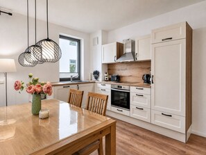 A modern kitchen with white cabinetry, a wooden countertop, a built-in oven, and a window with natural light.
