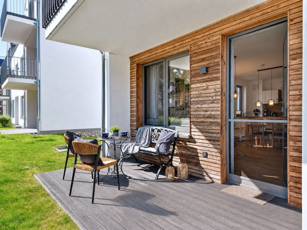 A modern outdoor seating area with a table and chairs, a small potted plant, and a wooden deck.