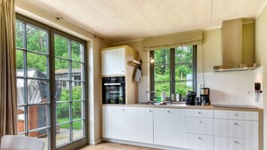 Une cuisine moderne dotée de grandes fenêtres, de meubles blancs et d’un four encastré.