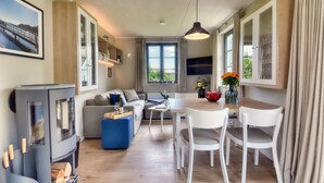 Un salon moderne avec un canapé, une table à manger et des chaises, un téléviseur et une cheminée.