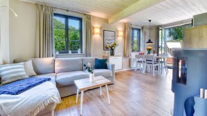 Uma sala de estar moderna com sofá, mesa de centro e área de jantar com cadeiras e mesa.