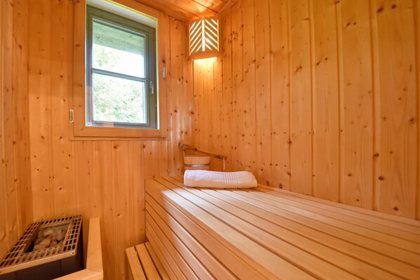 A wooden cabin room with a bed, a window, and a wall-mounted light fixture. - Newly built, modern, exclusive - that describes the Klein Stresow vacation village (Klein Stresow)