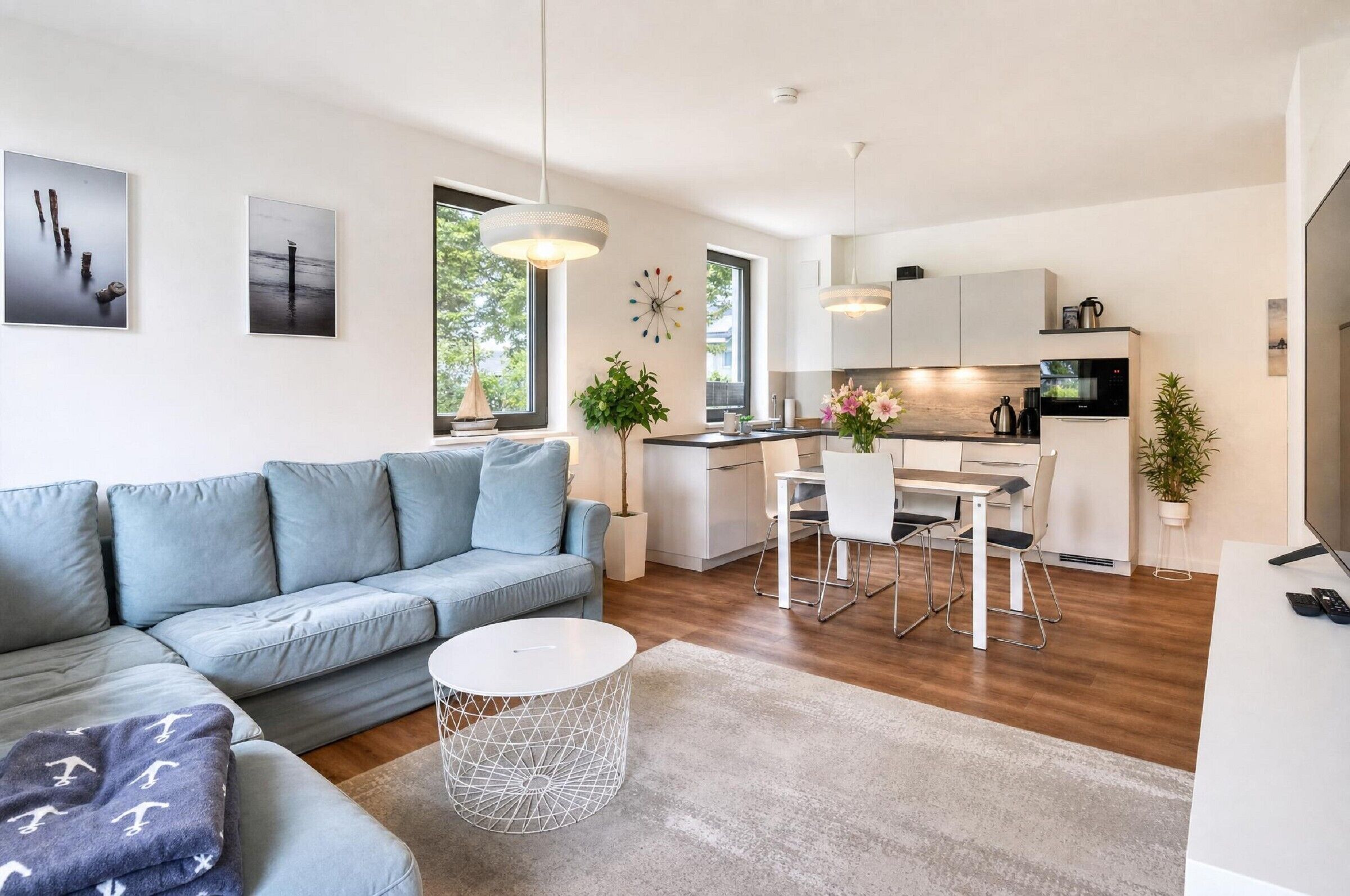 A modern living room with a sofa, a dining table, and a kitchen area with cabinets and appliances.