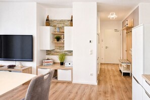 A modern living room with a flat-screen TV, wooden flooring, and a stone accent wall.