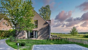 A modern house with a brick exterior, a paved driveway, and a well-maintained lawn. - Welcome to the Brick Quarter South Putbus on the island of Rügen (Putbus)