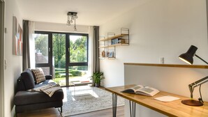 A modern living room with a sofa, a desk with a lamp, and a bookshelf. - Welcome to the Brick Quarter South Putbus on the island of Rügen (Putbus)