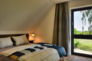Relax in a spacious room with a large bed, bedside table, and window offering a view of the outdoors.