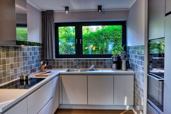 A modern kitchen with a large window, white cabinets, and a black countertop.