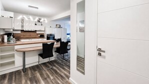 Una cucina moderna con mobili bianchi, un piano di lavoro in legno e sgabelli da bar neri.