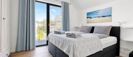 A bedroom with a bed, a view of the outside, and a painting on the wall.