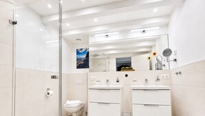 Un baño moderno con cabina de ducha de vidrio, inodoro y tocador doble.