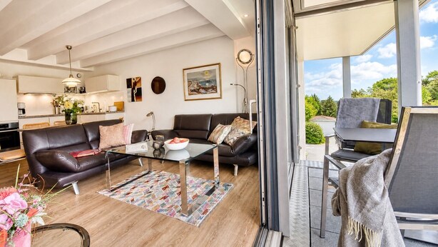 Una sala de estar moderna con una mesa de centro de vidrio, sofás de cuero y vistas al exterior.