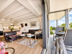 Un salon moderne avec une table basse en verre, des canapés en cuir et une vue sur l’extérieur.