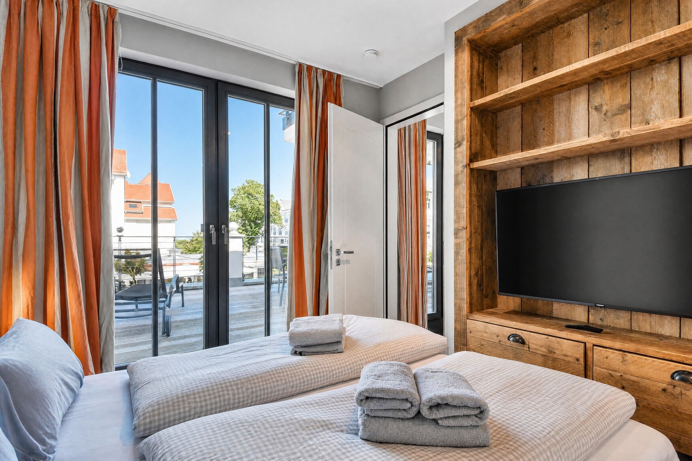 A hotel room with two beds, a television, and a sliding glass door leading to an outdoor area.