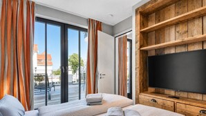 Une chambre d’hôtel avec deux lits, une télévision et une porte-fenêtre coulissante donnant sur un espace extérieur.