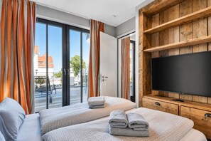 A hotel room with two beds, a television, and a sliding glass door leading to an outdoor area.