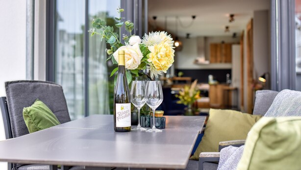A dining table with a bottle of wine, two wine glasses, and a bouquet of flowers. - Relaxed Baltic Sea vacation: vacation apartment Strandperle in Binz with lake view (Binz)