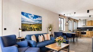 A modern living room with a blue sofa, a coffee table, and a painting of a landscape. - Relaxed Baltic Sea vacation: vacation apartment Strandperle in Binz with lake view (Binz)