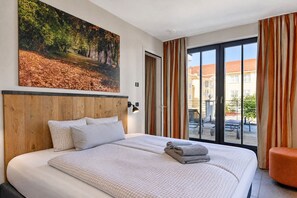 Une chambre d’hôtel avec un grand lit, un tableau au mur et une vue sur l’extérieur.