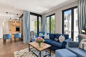 Una sala moderna con un sofá azul, una mesa de centro de madera y un comedor con sillas azules.