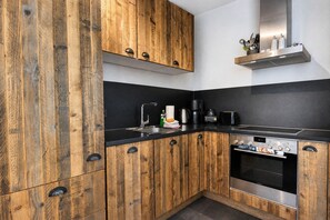 Une cuisine moderne avec des meubles en bois, un plan de travail noir, un four Siemens et une machine à café.