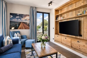 Una sala de estar moderna con un sofá, una mesa de centro y un televisor sobre una pared de madera.