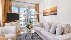 Una sala de estar moderna con un televisor de pantalla plana, un sofá, una mesa de centro y un cuadro de un atardecer.