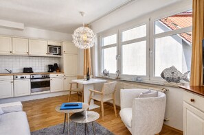 Una cocina moderna con armarios blancos, un microondas y un comedor con mesa y sillas.