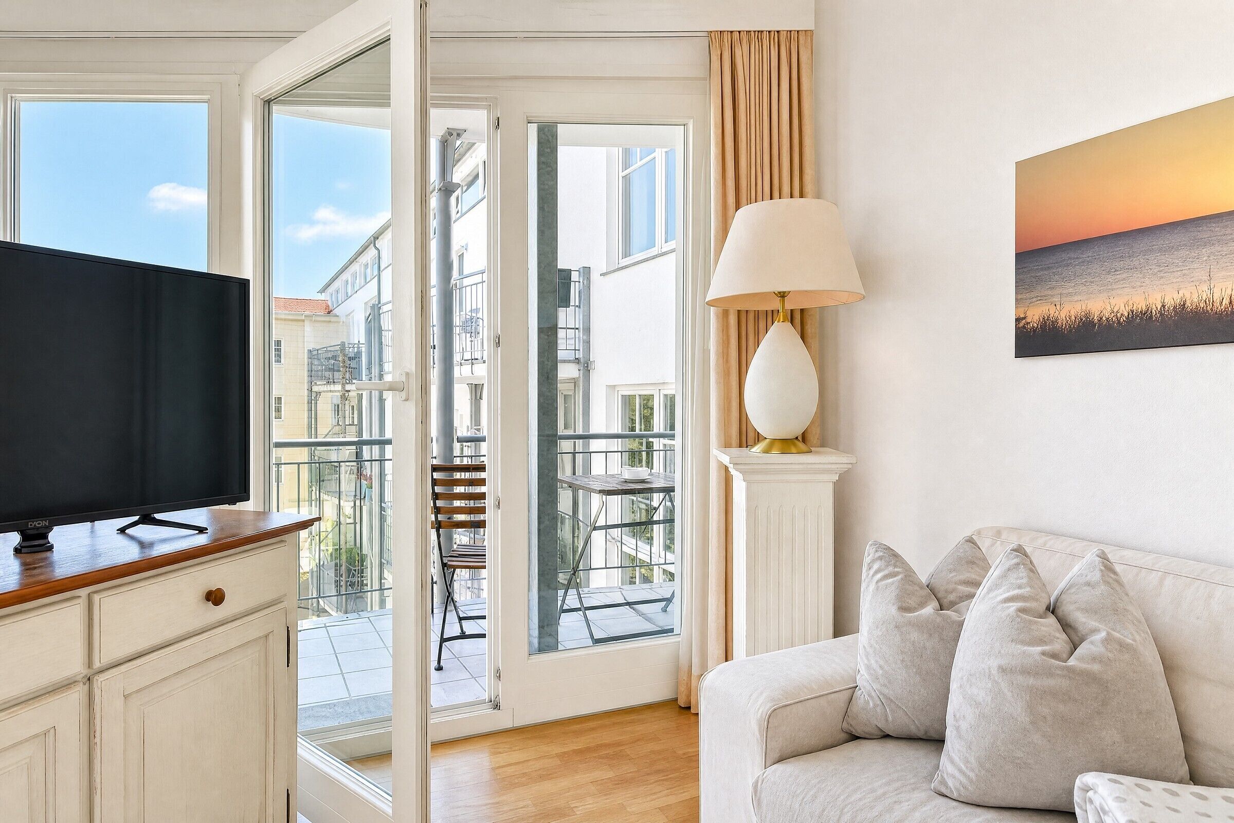Una sala de estar con televisión, sofá, lámpara y un cuadro.
